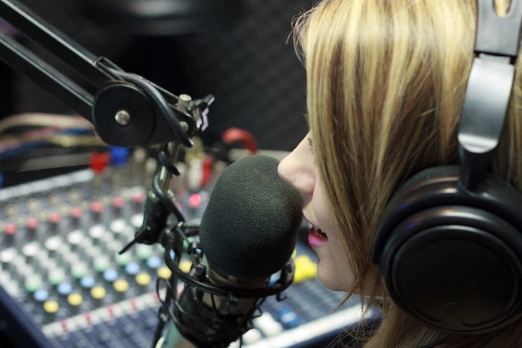 Woman speaking into a microphone in a radio studio.